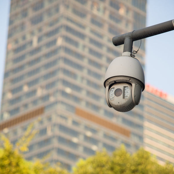 Security camera on a pole with city buildings in the background