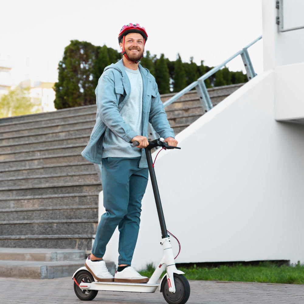 Man riding an electric scooter outdoors near a modern building.