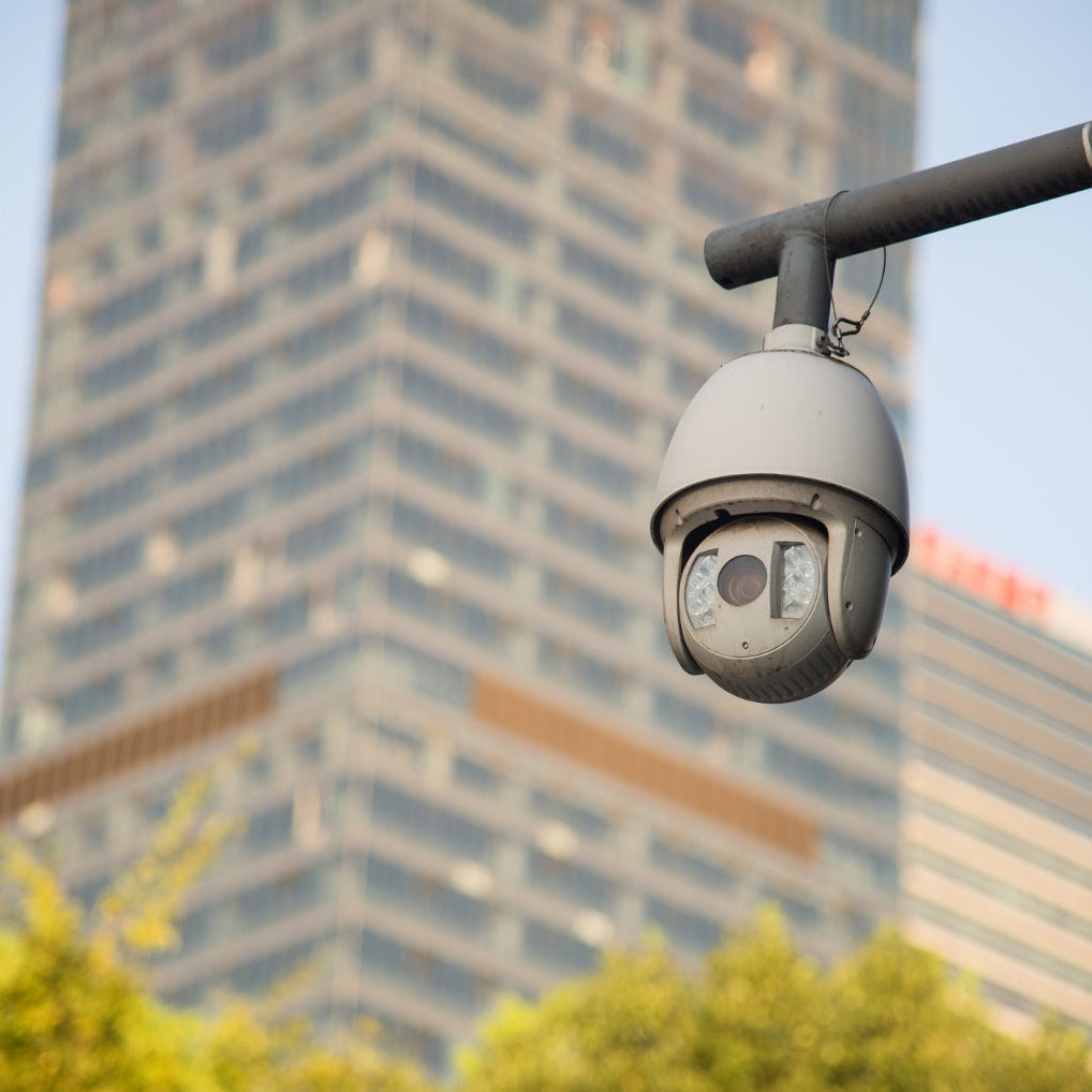 Security camera on a pole with city buildings in the background